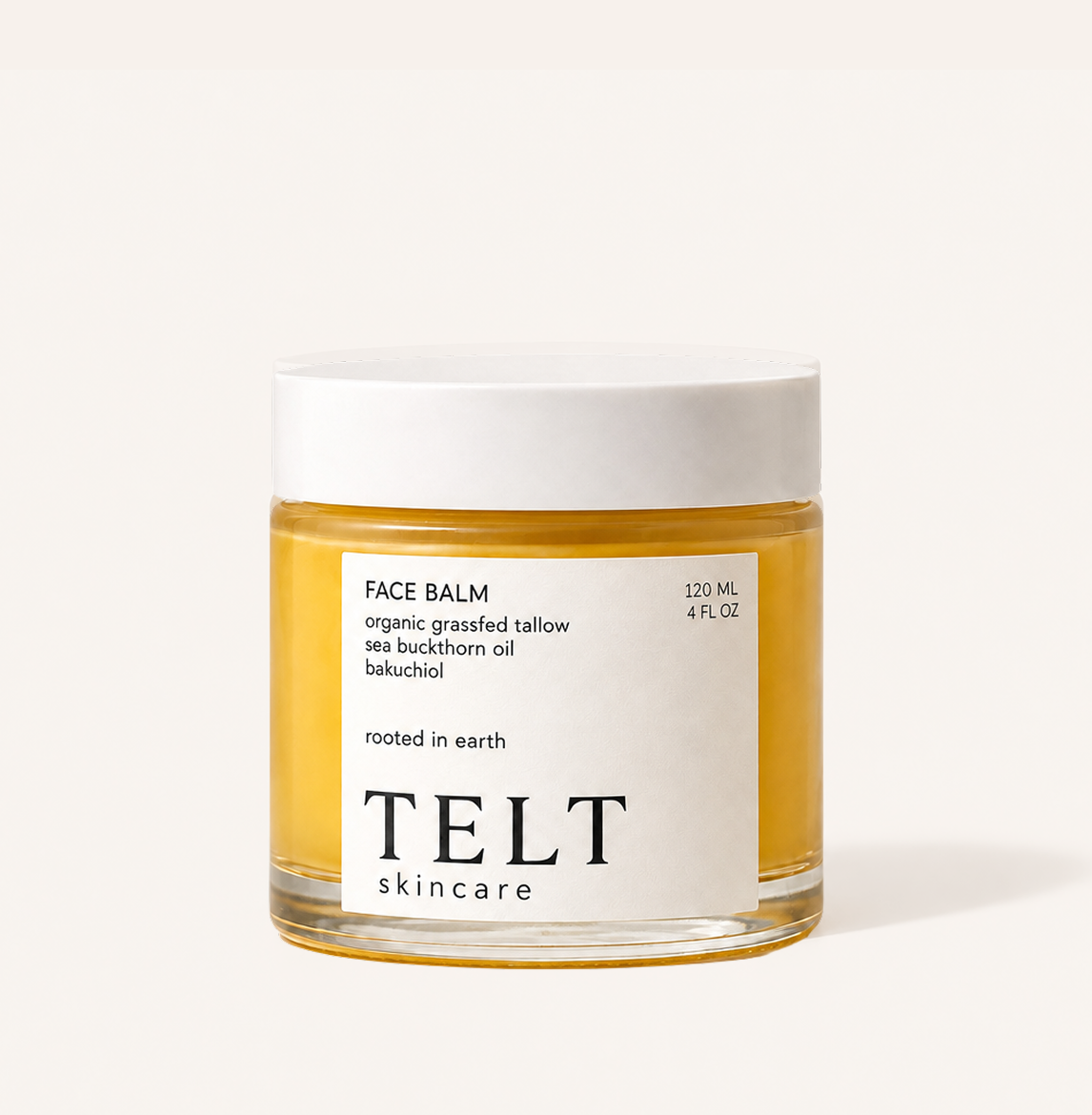 A glass jar of Telt Skincare Face Balm with a white lid and a white label, filled with golden-yellow balm, set against a solid off-white background.